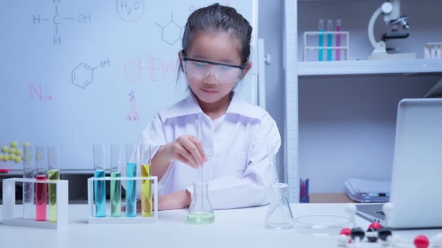 Young asian girl conducting science experiment with colorful liquids in classroom laboratory for education and stem learning concept	