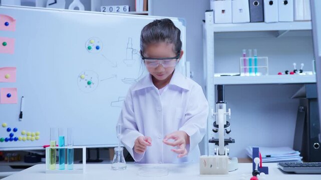 Little asian scientist girl examining glass slide under microscope in science laboratory for chemistry research and education