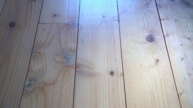 Slow tilt shot, pine wood floor close up shot, entering morning light through the window.