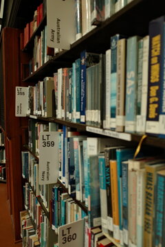 australian military history library shelves with categorized books army navy sas defense studies organized spines academic research section