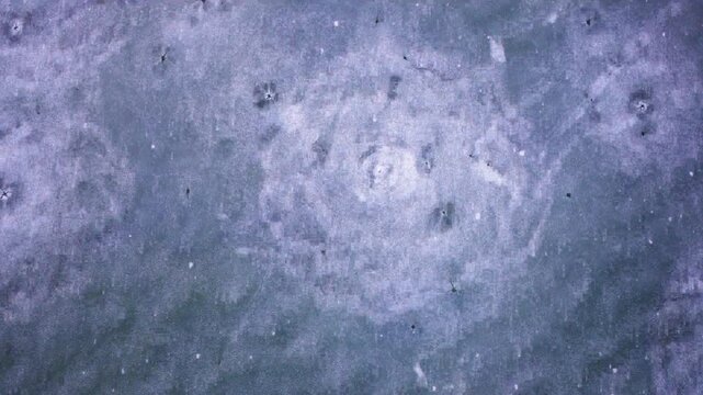 Aerial view of frozen lake surface with natural circular patterns and bubbling texture during winter.