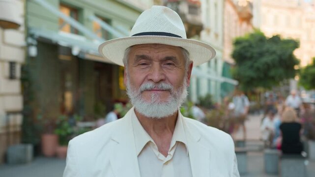Close up portrait of calm elderly gray haired Caucasian man looking at camera on city street intelligent retired businessman aged healthy senior male older tourist travelling medical service outdoors