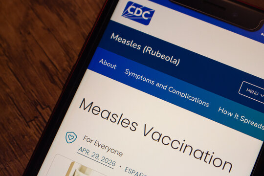 Mexico City, MEXICO - Sep 1 2026 : Close-up of a smartphone on a dark wooden surface displaying the CDC Measles Vaccination page dated April 29, 2026, within the Measles (Rubeola) topic section.