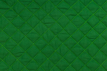 Green quilted fabric texture with diamond stitching © Iryna Miadzvedzeva