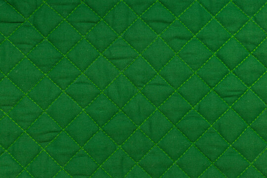 Green quilted fabric texture with diamond stitching
