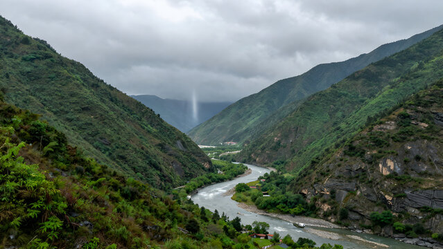 River flowing through a deep green mountain valley under cloudy sky