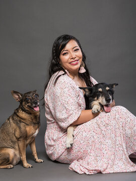 Woman Sitting with Two Dogs in a Studio on Gray Background