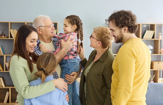 Family grandparents parents children mother father hug together. Warm multigenerational reunion in a cozy home, smiling and embracing for lifestyle use. Symbolic message of family unity.
