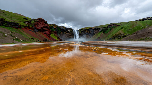 Volcanic landscape with waterfall and colorful hot spring runoff