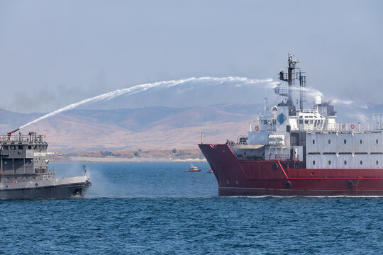 A fire ship extinguishes a fire on a vessel ship after attack with drone.
