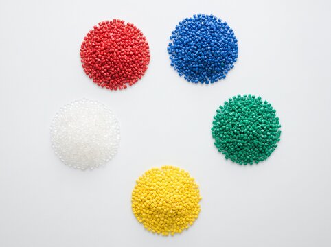 Circular arrangement of colorful plastic pellets on white background