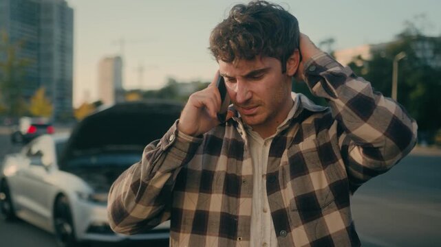 Confused anxious Caucasian business man calling car service beside broken auto in city stressed male guy driver talking mobile phone need tow truck assistance for vehicle breakdown on road outdoors