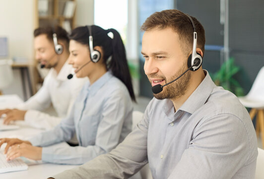 Callcenter operator with headset supports customers. Coworkers work at PCs in modern office using tech to answer inquiries and ensure communication. Customer service and teamwork concept.