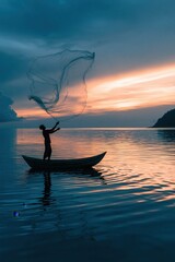 Obraz premium A fisherman in silhouette is captured mid action, casting a large circular net from a small boat on a still lake during sunset.