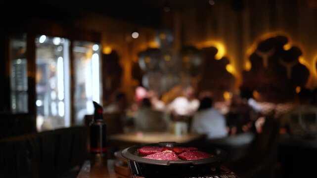 Chef cooks beef steak, sprinkling with salt on a background of restaurant.