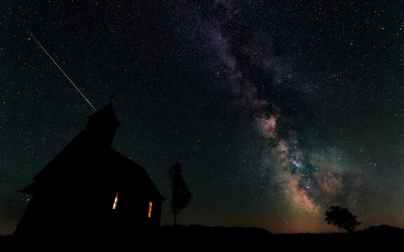 A Perseid meteor streaks across the night sky above the illuminated Gahberg chapel, with the Milky Way rising over the Attersee region, Weyregg am Attersee, Salzkammergut, Upper Austria, Austria