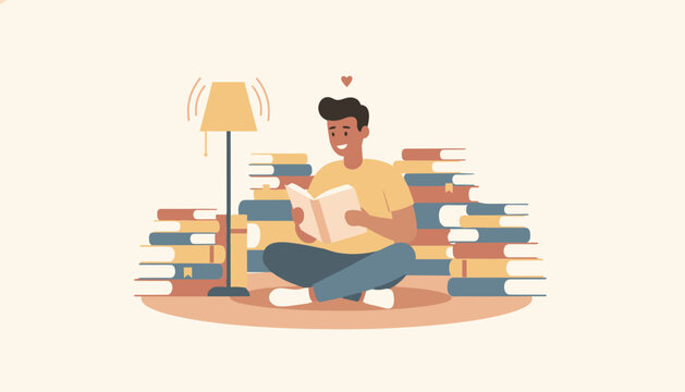 Happy young man sitting cross legged on the floor reading a book among tall stacks of books under a glowing lamp.