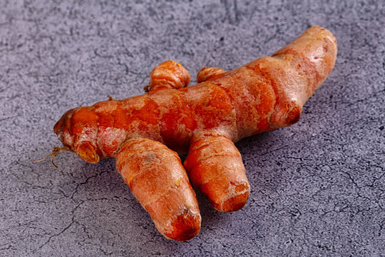 Fresh turmeric root on textured gray surface