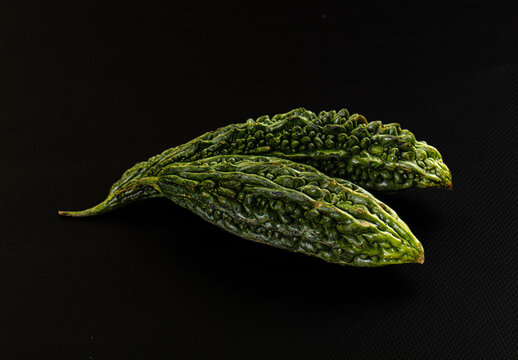 Two green bitter gourds on black background