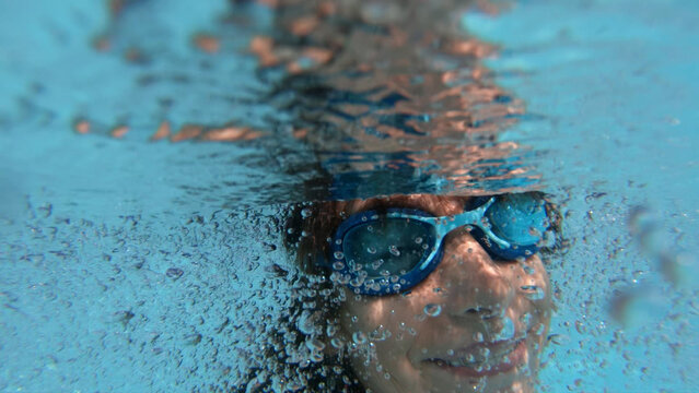 Young girl swimming underwater with air bubbles