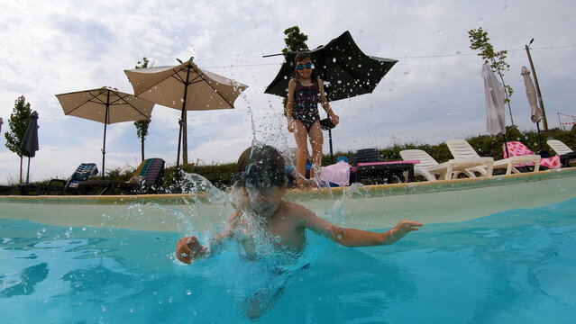Young boy jumping and splashing into a blue swimming pool underwater