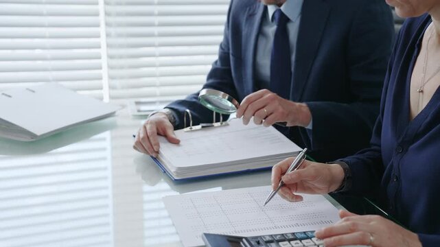 Professional auditors and accountants reviewing financial documents, discussing data, calculating taxes and expenses during an important business audit meeting