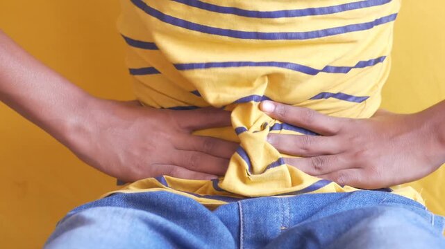 Close up view of young person experiencing severe stomach pain, clutching abdomen, indicating digestive discomfort or illness, dynamic footage