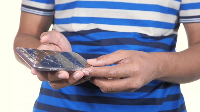 Hands holding broken smartphone screen with visible glass cracks and damage