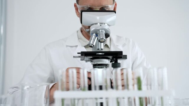 Scientist in lab coat and safety glasses looking through a microscope, performing detailed research for scientific discovery, experimenting with samples in a modern laboratory setting