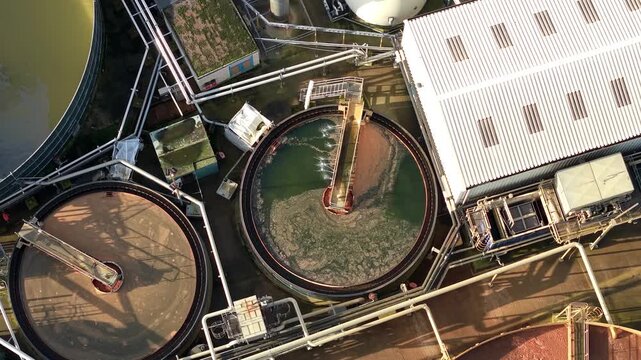 Aerial view of circular industrial clarifier tanks processing wastewater in treatment facility.