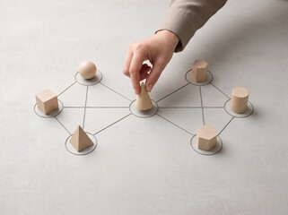 Obraz premium Hand Placing Wooden Geometric Shape on Network Diagram
