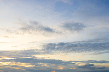 Obraz premium Soft morning sky with gentle clouds and golden light,A wide view of a peaceful blue sky illuminated by soft golden sunlight, filled with gentle wispy clouds during early morning sunrise or evening.