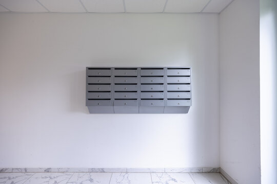 Gray Mailboxes Mounted in Minimal Apartment Hallway With Marble Floor and Soft Natural Light