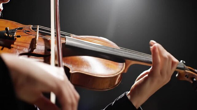 Close up of a musician playing a classical violin in a dark studio