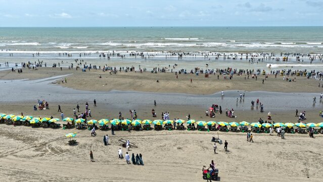 Aerial view of Sugondha Sea Beach with numerous people relaxing under rows of colorful umbrellas along the sandy coastline in Cox's Bazar, Chittagong Division, Bangladesh.