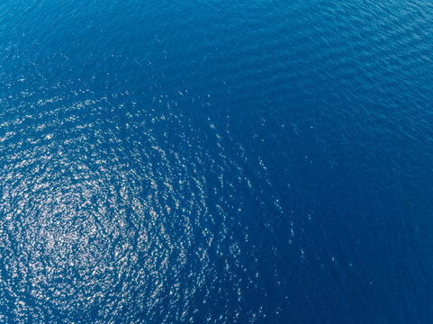 Aerial view of calm ocean water with sunlight reflections
