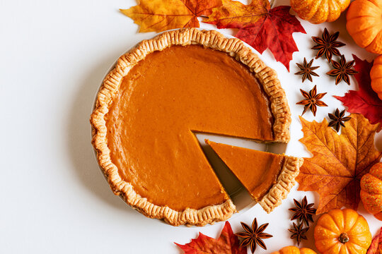 Sliced pumpkin pie with autumn leaves, star anise and mini pumpkins, Thanksgiving flat lay
