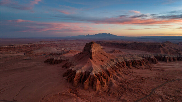 Aerial view of Goblin Valley State Park featuring unique sandstone formations and rugged desert terrain under a soft pink and blue sunset sky in Green River, Utah, United States.