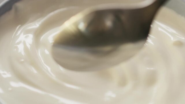 Slow motion scoop white yogurt with spoon closeup