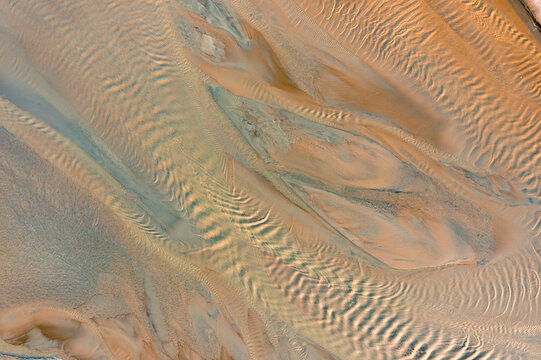 Aerial view of intricate sediment patterns and textures formed by water flow in a riverbed in Poland.