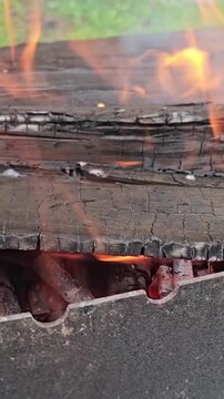 Fire burning through a wooden surface in an outdoor setting during the day