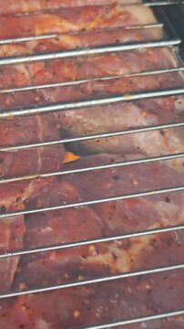 Grilling meat with seasoning on a barbecue in a backyard during summer