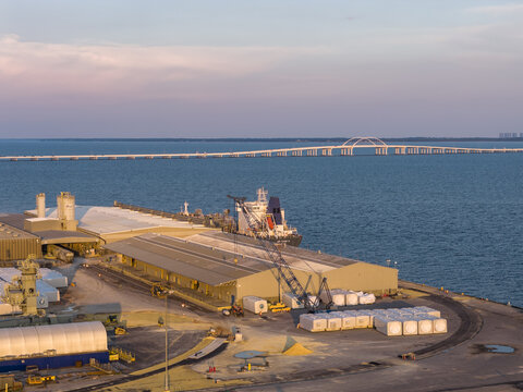 Aerial view of the CEMEX Pensacola Cement Import Terminal with a cargo ship at the pier, industrial warehouses, and storage areas along the waterfront in Pensacola, Florida, United States.