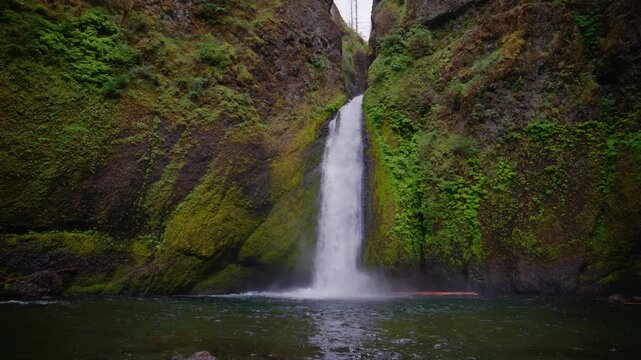 Wahkeena Falls drops into a calm pool framed by vivid mossy cliffs and Oregon greenery, medium low static