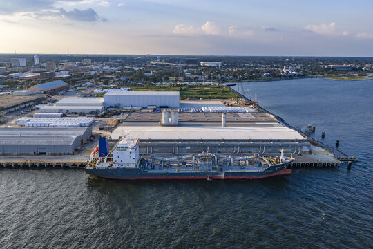 Aerial view of the CEMEX Pensacola Cement Import Terminal with a cargo ship docked at the pier, industrial warehouses, and the Pensacola city skyline, Pensacola, Florida, United States.