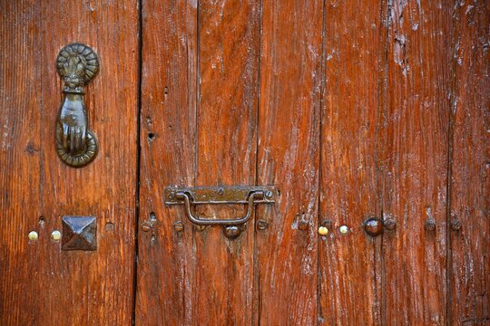 Antique wooden door with a vintage brass knocker, rusty studs and handle in the historic center of Santiago de Quer&eacute;taro, Mexico.