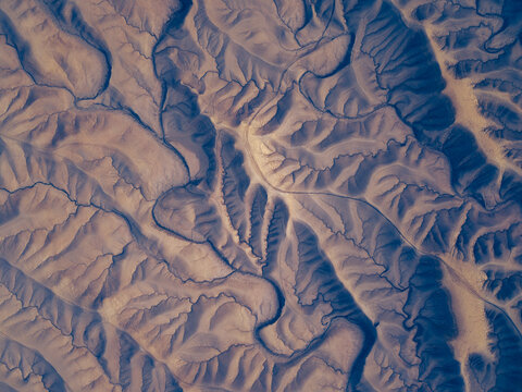 Aerial view of the rugged badlands and intricate drainage patterns surrounding Factory Butte, showcasing the dramatic desert landscape in Wayne County, Utah, United States.