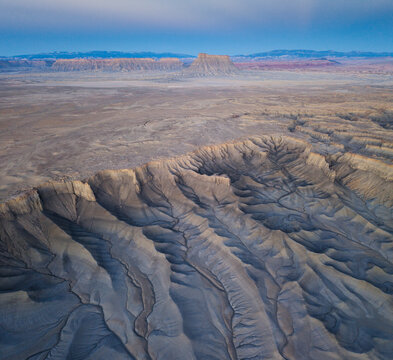 Aerial view of Factory Butte rising above the rugged, eroded badlands and desert landscape of Wayne County, Utah, United States.