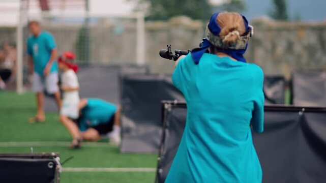 A person holding a laser tag gun is taking aim at an open shooting range in bright daylight