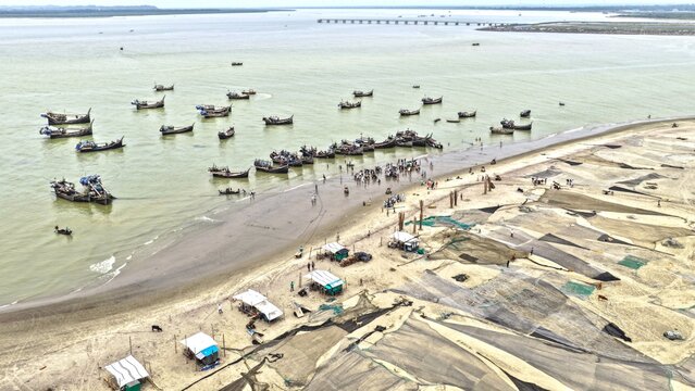 Aerial view of Cox's Bazar beach with wooden fishing boats anchored in the water and large fishing nets spread out to dry on the sand, Cox's Bazar, Chittagong Division, Bangladesh.